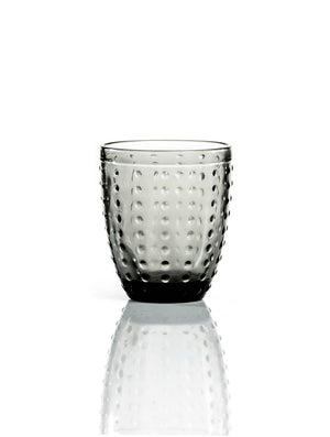 The Dotty Smoke Tumbler features modern grey-tinted glass with a rounded shape and textured dimpled surface, shown on a white background with a subtle reflection.