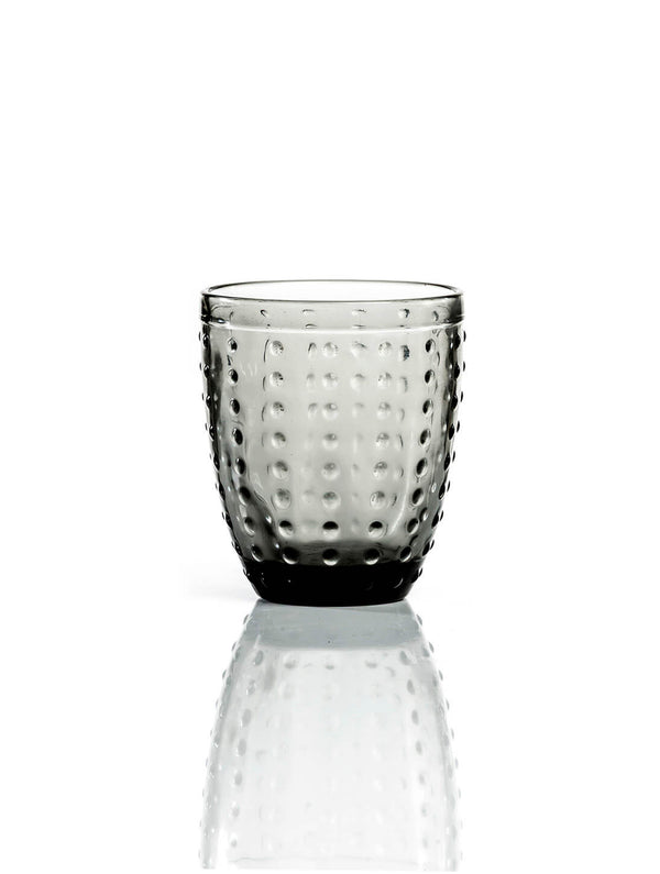 The Dotty Smoke Tumbler features modern grey-tinted glass with a rounded shape and textured dimpled surface, shown on a white background with a subtle reflection.