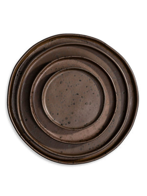 Part of the Juniper Plate Range, this handcrafted round ceramic plate features a rustic dark brown glaze, uneven rim, and scattered speckles, showcased against a white background.