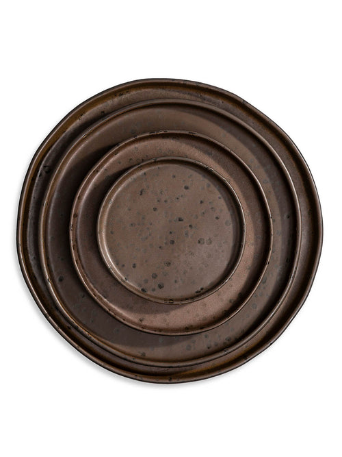 Part of the Juniper Plate Range, this handcrafted round ceramic plate features a rustic dark brown glaze, uneven rim, and scattered speckles, showcased against a white background.