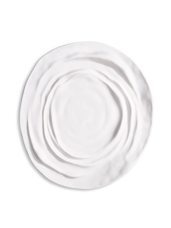 The Lavina Plate is a white ceramic plate with an irregular, wavy textured surface and uneven edges—an elegant piece for any luxury dinnerware collection.