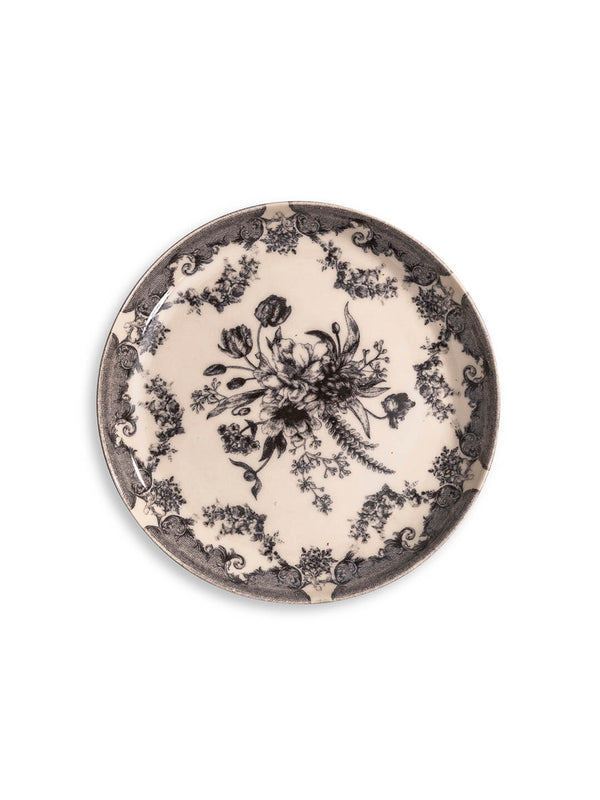 The Lucinda Black Plate Range features round plates with ornate black floral centers and intricate decorative borders on a cream background—perfect for adding vintage-inspired elegance to modern tablescapes. Photographed on a white surface.