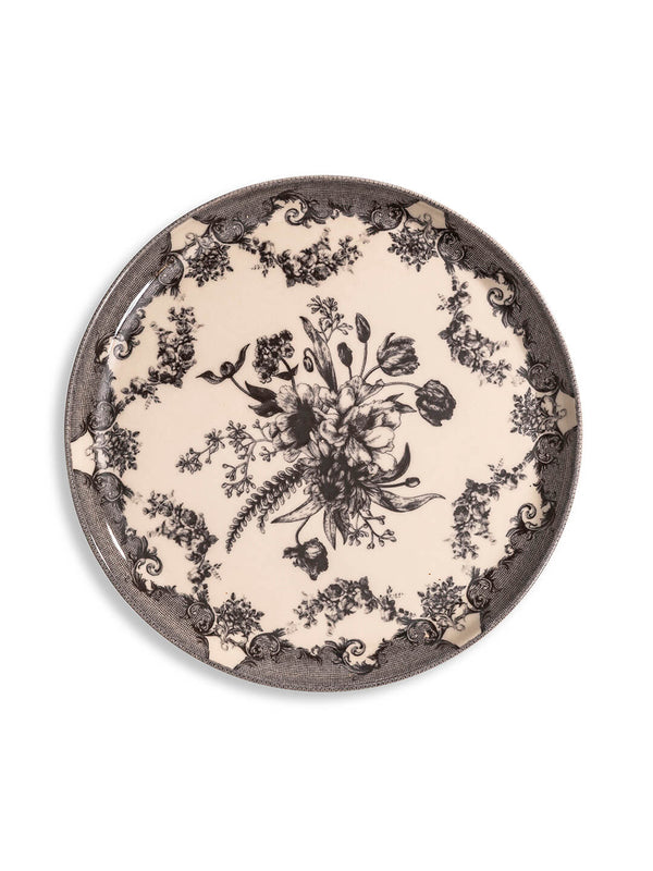 The Lucinda Black Plate Range features round ceramic plates with vintage-inspired black floral patterns and ornate scrollwork on a cream background—perfect for adding timeless elegance to modern tablescapes.