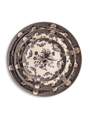 The Lucinda Black Plate Range features three vintage-inspired plates with intricate black floral and scroll designs on a cream background, stacked on a white surface—ideal for elevating modern tablescapes.