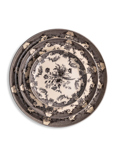 The Lucinda Black Plate Range features three vintage-inspired plates with intricate black floral and scroll designs on a cream background, stacked on a white surface—ideal for elevating modern tablescapes.