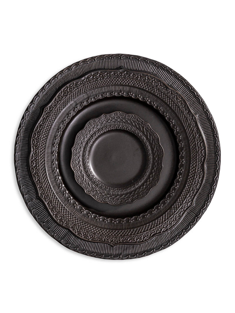 Three stacked matte black plates from the Noir Plate Range, each a different size and featuring embossed rim patterns, are centered on a white background.