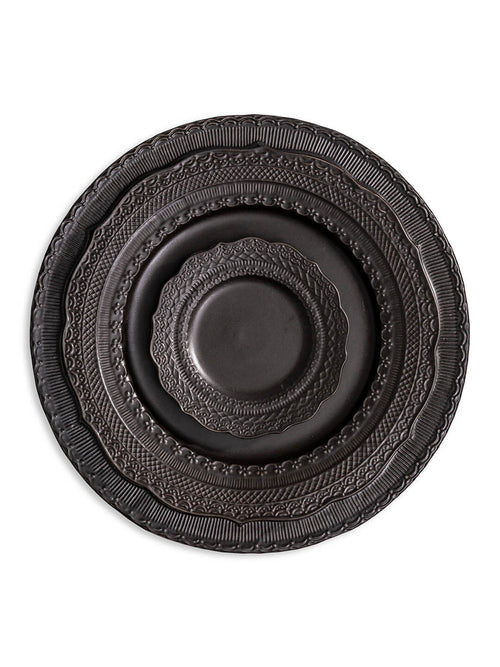 Three stacked matte black plates from the Noir Plate Range, each a different size and featuring embossed rim patterns, are centered on a white background.