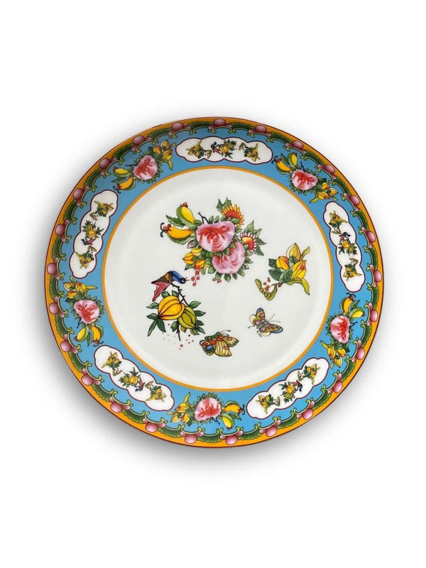 The Paloma Plate Range features blue and white borders with colorful flowers, butterflies, and birds. Pink roses, yellow blooms, and mandala-inspired patterns add decorative charm at the center and rim of this vibrant tableware.