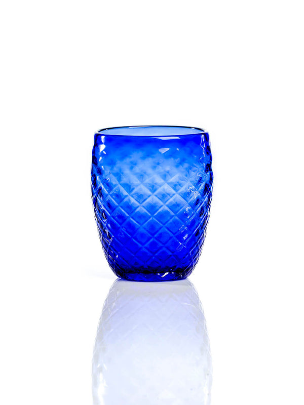 The Prisma Blue Tumbler displays a diamond-patterned texture for a modern look. This blue tumbler rests on a reflective white surface set against a plain white background.