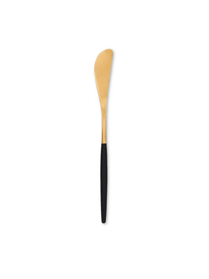 A gold butter spreader from the Raven Cutlery Range with a curved blade and sleek black handle is displayed on a white background‚Äîideal for anyone seeking stylish, modern tableware.