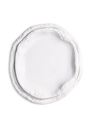 A white, round ceramic plate from the Rocca Plate Range, featuring an irregular textured and layered edge, is displayed against a plain white background as part of a luxury fine dining collection.