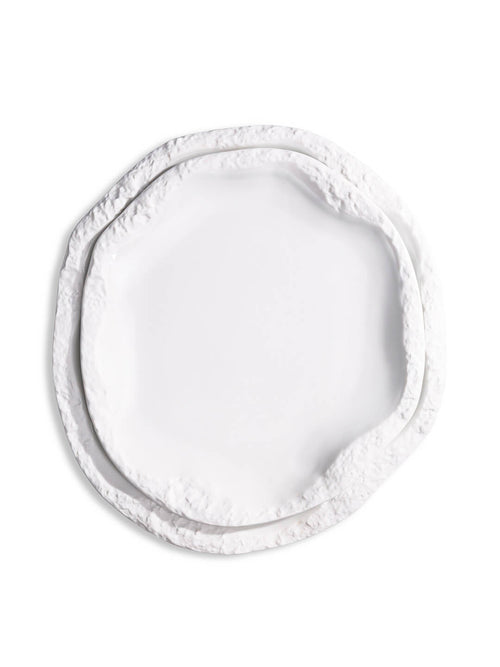 A white, round ceramic plate from the Rocca Plate Range, featuring an irregular textured and layered edge, is displayed against a plain white background as part of a luxury fine dining collection.