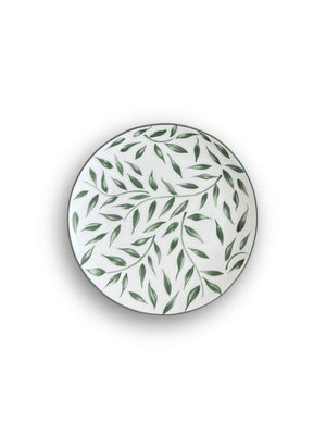 The Willow Plate Range features round white ceramic plates adorned with a scattered green leaf motif, shown from above on a white background for a fresh botanical look.