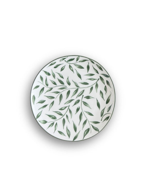 The Willow Plate Range features round white ceramic plates adorned with a scattered green leaf motif, shown from above on a white background for a fresh botanical look.