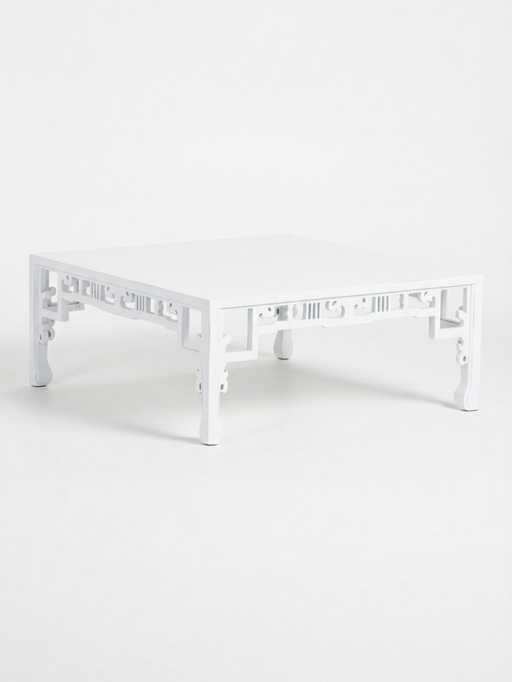 The Bali Blanc Table is a modern coffee table with a high-gloss white finish, decorative cutout side patterns, and gently curved legs, showcasing Eastern-inspired design.
