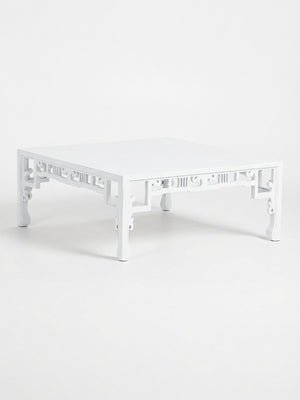 The Bali Blanc Table is a modern coffee table with a high-gloss white finish, decorative cutout side patterns, and gently curved legs, showcasing Eastern-inspired design.