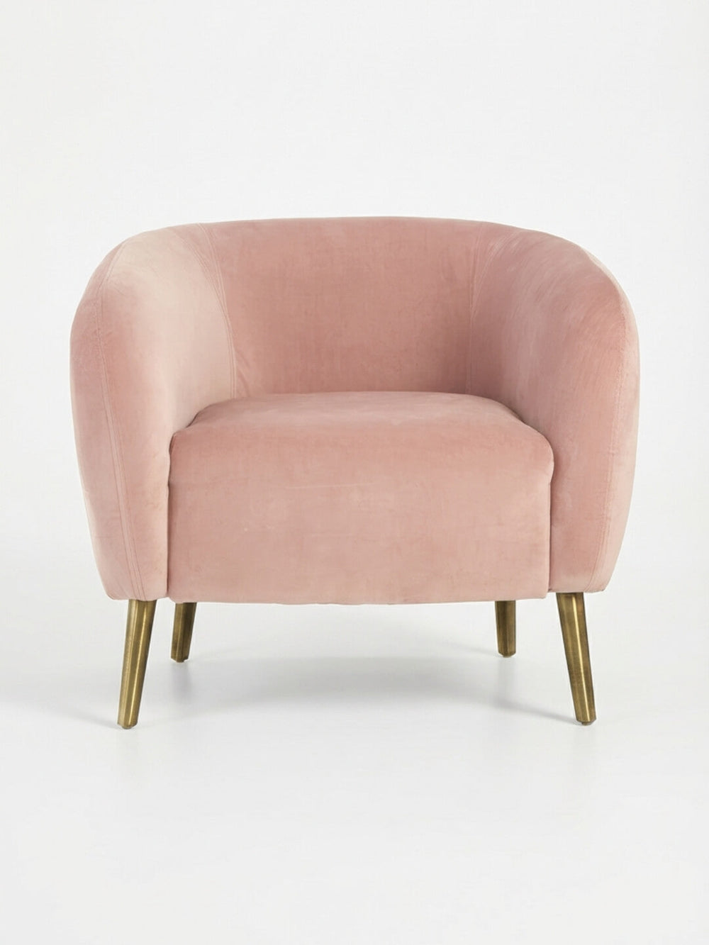The Bellevue Chair is a blush pink velvet armchair with a curved back and seat, set on angled slender gold metal legs—a modern statement piece perfect for accenting any plain white background.