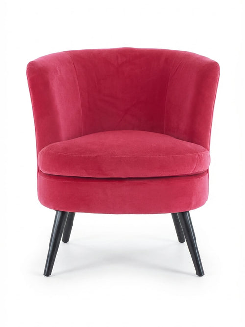 The Berry Chair is a modern lounge chair with a curved backrest, bright pink velvet upholstery, plush seat cushion, and four angled black wooden legs, offering sleek contemporary style as a velvet accent chair.
