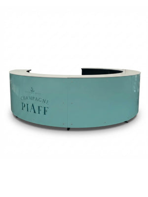 The Bespoke Branded Bar features a curved, light teal front with a Champagne Piaff and small crest logo, plus a white countertop. Its plain background makes it a versatile, customisable solution for events or receptions.