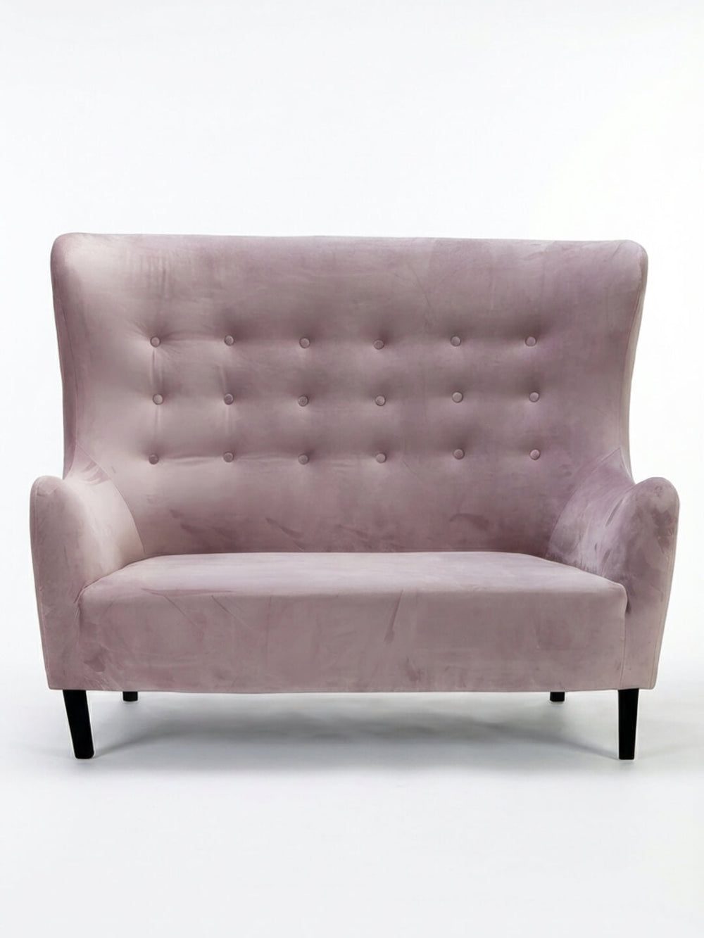 The Cameo Sofa features modern pink velvet, a high back, button-tufted upholstery, curved arms, and black tapered legs—making it a bold statement piece on any plain white background.