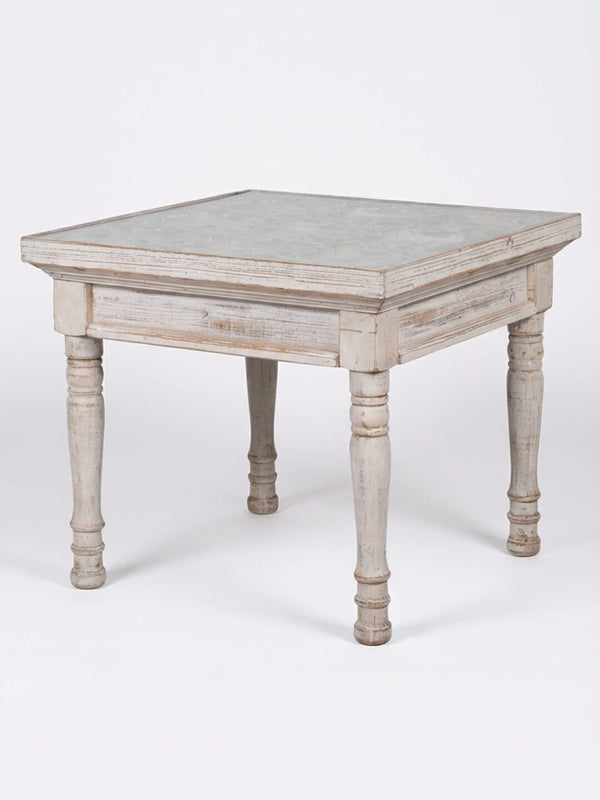 The Chantilly Side Table is a square, rustic wooden table with a weathered finish and four turned legs, adding French elegance as a wedding accent against a plain white background.