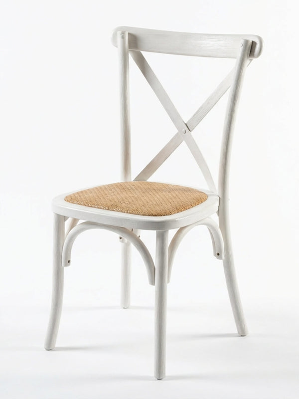 The Cross Back Chair features a curved backrest, X-shaped design, and light brown woven rattan seat—perfect for wedding chair hire or rustic event furniture. Shown here in white against a plain background.