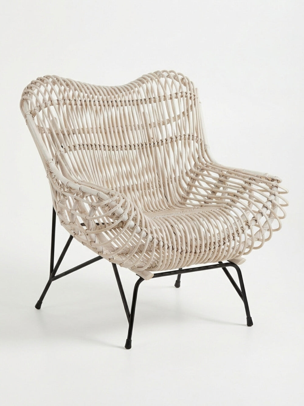 The Driftwood Lounge Chair features light-colored woven rattan, a curved back and seat, and outward-angled black metal legs. Weather-resistant, this modern lounge chair is ideal for stylish outdoor relaxation.