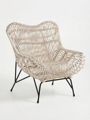 The Driftwood Lounge Chair features light-colored woven rattan, a curved back and seat, and outward-angled black metal legs. Weather-resistant, this modern lounge chair is ideal for stylish outdoor relaxation.