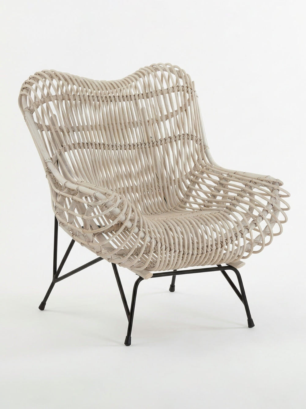 The Driftwood Lounge Chair features a wide, modern design with light woven rattan, curved edges, black metal legs, and weather-resistant construction, shown against a plain white background.
