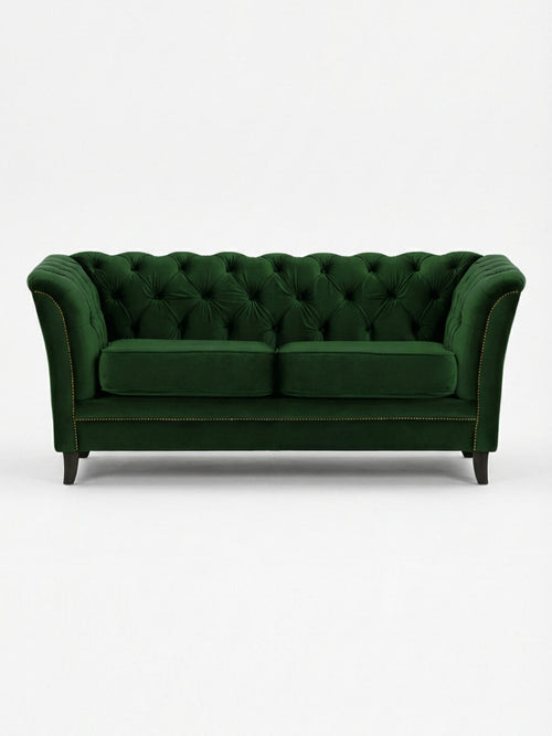 The Eden Sofa, upholstered in dark green velvet with tufted details, curved arms, two seat cushions, and dark wooden legs, offers a touch of modern luxury to any space.