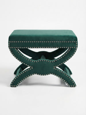 The Eden Stool features a green velvet rectangular cushioned top, silver nailhead trim, and a decorative X-shaped base, providing stylish statement seating against a plain white background.