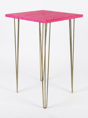 A compact square table from our Hairpin Bar Table Collection features a vibrant pink top and four slender gold metal hairpin legs—ideal as colourful event furniture. Pictured on a plain white background.
