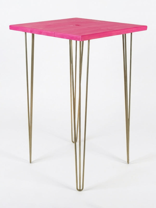 A compact square table from our Hairpin Bar Table Collection features a vibrant pink top and four slender gold metal hairpin legs—ideal as colourful event furniture. Pictured on a plain white background.