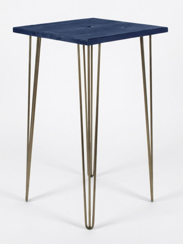 The Hairpin Bar Table Collection offers a compact bar table with a vivid blue wood square top and four slim, gold metal hairpin legs, photographed on a plain white background.