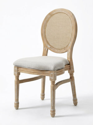 The Louis Rattan Chair features a natural wood finish with subtle white accents, a round cane backrest, cushioned light gray seat, carved details, and elegant French-inspired design.