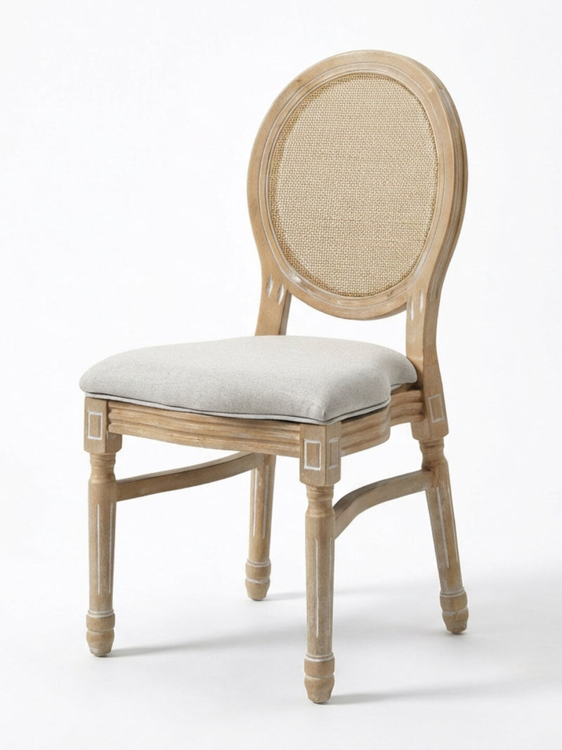 The Louis Rattan Chair features a natural wood finish with subtle white accents, a round cane backrest, cushioned light gray seat, carved details, and elegant French-inspired design.