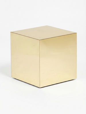 A polished, gold-colored metallic cube from the Luxe Cube Collection with smooth, reflective surfaces rests on a plain white background—perfect as event furniture or a striking accent to modern cube tables.