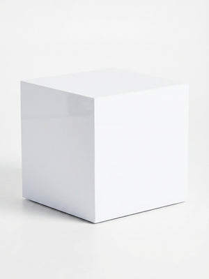 A glossy white table from the Luxe Cube Collection sits on a white surface with a faint shadow cast to one side against a white background.