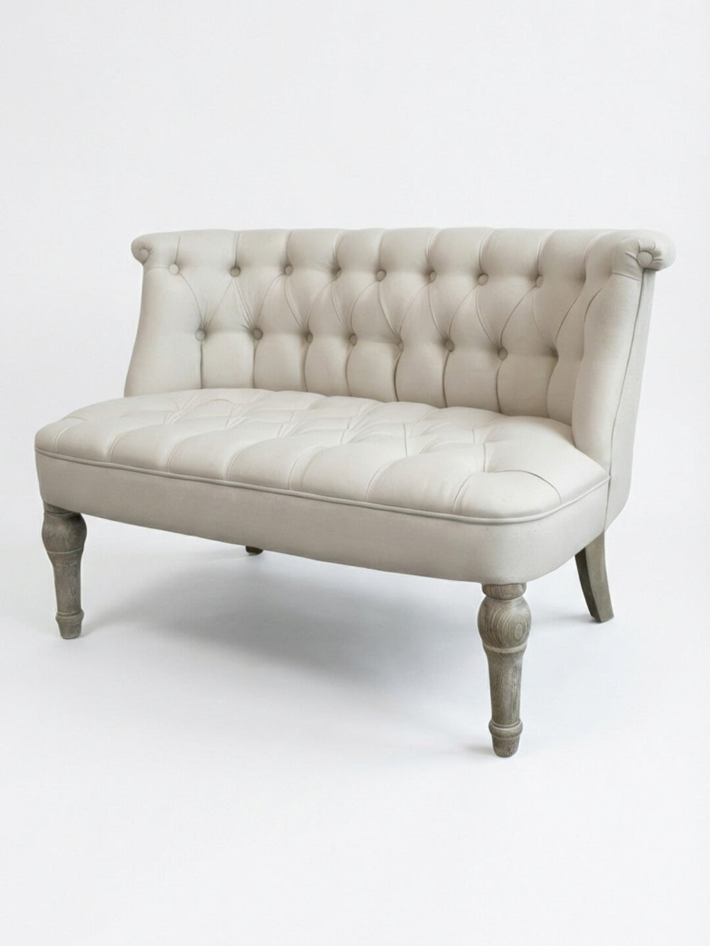 The Maison Sofa loveseat showcases French elegance with light gray linen upholstery, a tufted curved backrest, wooden legs, and an upholstered seat, displayed against a plain white background.