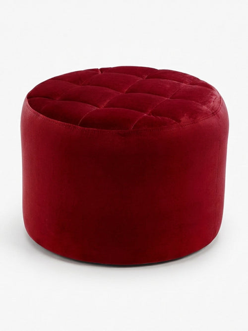 The Merlot Pouffe is round and deep red with a tufted, cushioned top and smooth sides, shown against a plain white background.