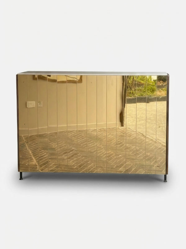 The Mirror Bar is a sleek, rectangular mirrored cabinet with a reflective golden front and four short black legs—an elegant, customisable piece ideal for stylish gatherings or event bar furniture.