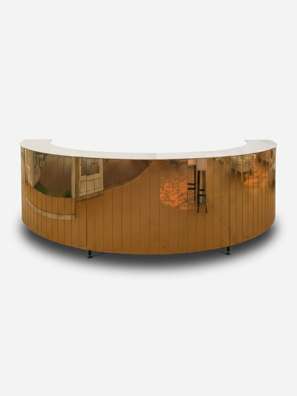 The Mirror Bar is a curved, gold-colored mirrored reception desk with a reflective surface, ideal as a luxury party bar or customizable event bar, shown against a plain white background.
