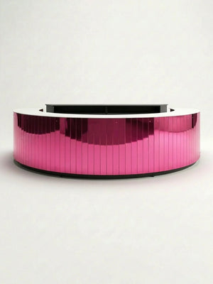 The Mirror Bar is a circular, modern reception desk featuring a glossy, reflective pink exterior and a white countertop, set against a plain white background.