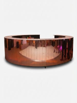 The Mirror Bar is a circular, shiny rose gold bar with a cut-out section that reflects floors, people, and lights—ideal as a customizable luxury event bar.