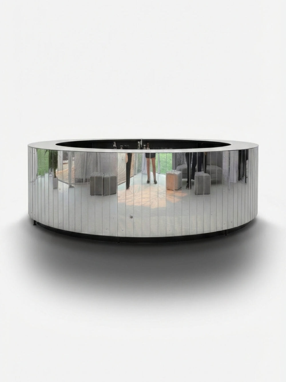 The Mirror Bar features a sleek, curved design with a reflective metallic surface that showcases the surrounding room, from clothing racks to polished wood floors. Set against a plain white background, it’s an ideal customizable event bar for stylish gatherings.