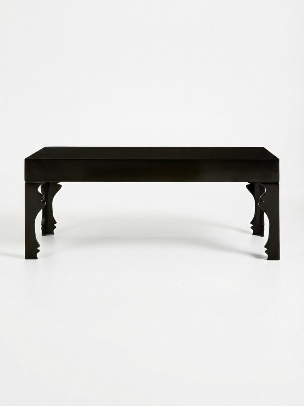The Muse Coffee Table is rectangular and black, with a smooth top and sculptural legs featuring elegant curves, showcased against a plain white background.