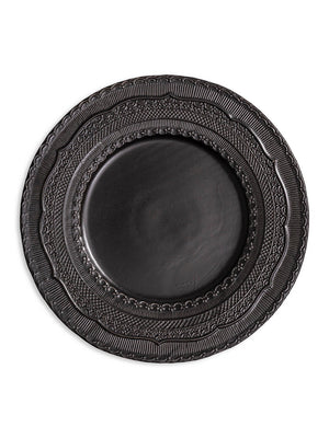 The Noir Charger Plate is a round, dark ceramic plate featuring a glossy finish and intricate raised patterns on its wide rim, ideal for luxurious tablescapes.
