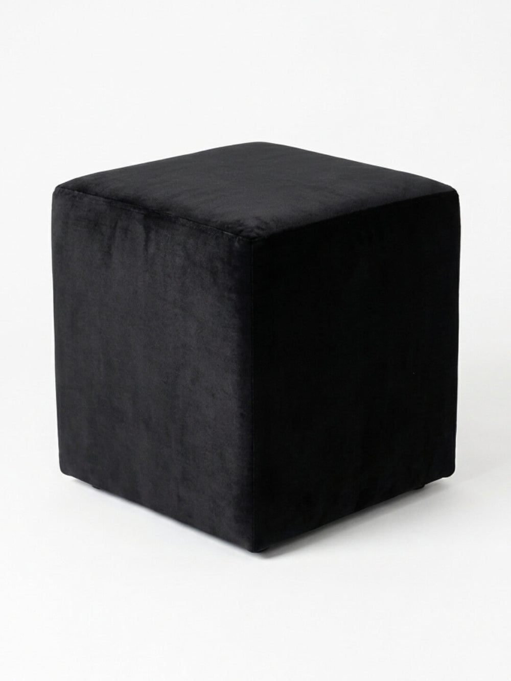 The Noir Cube, a sleek black velvet ottoman, is displayed on a plain white background and offers stylish minimalist seating for modern spaces.