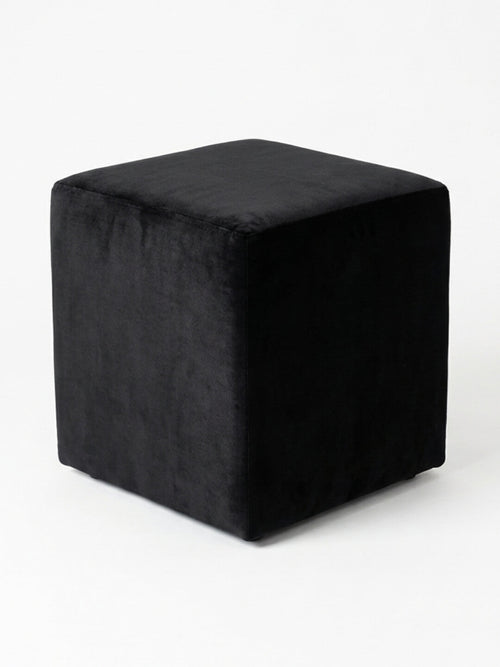 The Noir Cube, a sleek black velvet ottoman, is displayed on a plain white background and offers stylish minimalist seating for modern spaces.