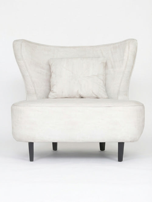 The Pearl Chair is a modern accent chair in light beige, featuring a winged backrest, matching square cushion, and dark wooden legs.